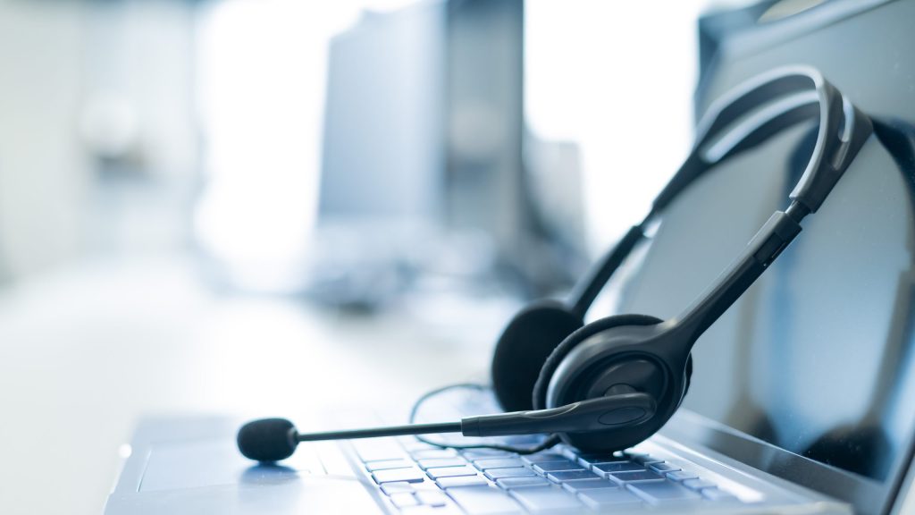 Call center operator desktop. Close-up of a headset on a laptop. Help desk. Workplace of a support service employee. Headphones with a microphone for voip on a computer keyboard